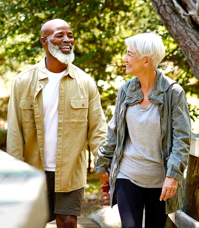 A smiling senior couple walking outside on a bridge.